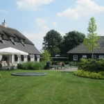 Terras met trampoline van parktuin in Vianen. Tuinaanleg door Uw Tuin Hoveniers uit Malden