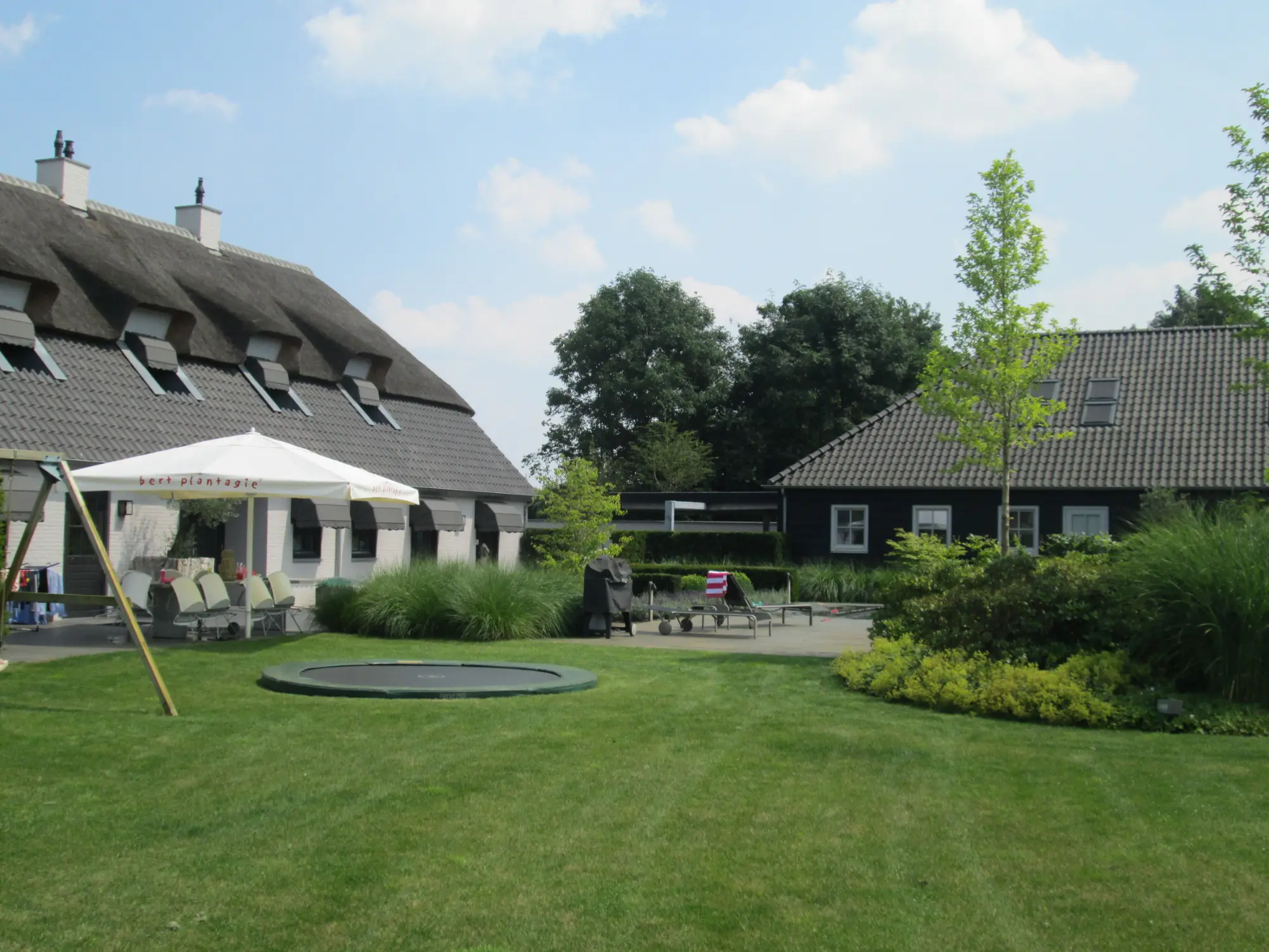 Terras met trampoline van parktuin in Vianen. Tuinaanleg door Uw Tuin Hoveniers uit Malden