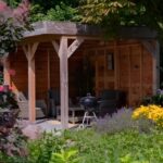 Tuinaanleg van een bostuin met tuinoverkapping in Huissen. Volle borders met kleurrijke beplanting.