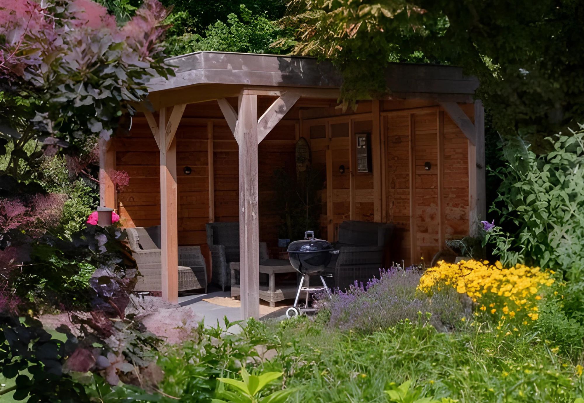 Tuinaanleg van een bostuin met tuinoverkapping in Huissen. Volle borders met kleurrijke beplanting.