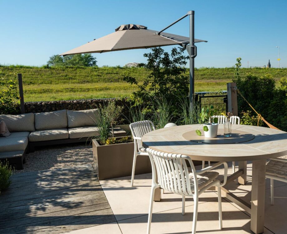 Stadstuin in Nijmegen Noord. Met prachtig uitzicht over het landschap. Opentuin met verschillende terrassen. Groene oase. Keramisch terras, grind en vlonderpad. Postzegeltuin aan het landschap met uitzicht op de dijk van de Waalbrug.