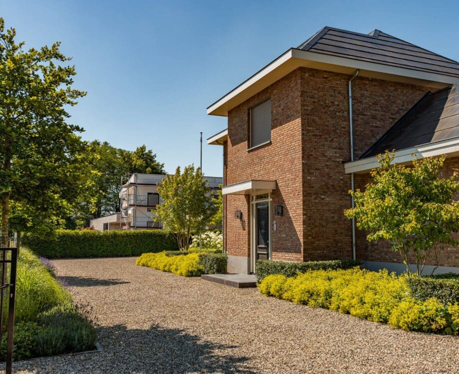Vooraanzicht van een klassiek huis met een groene tuin in Malden. Tuinontwerp, tuinaanleg en tuinonderhoud door Uw Tuin Hoveniers uit Malden.
