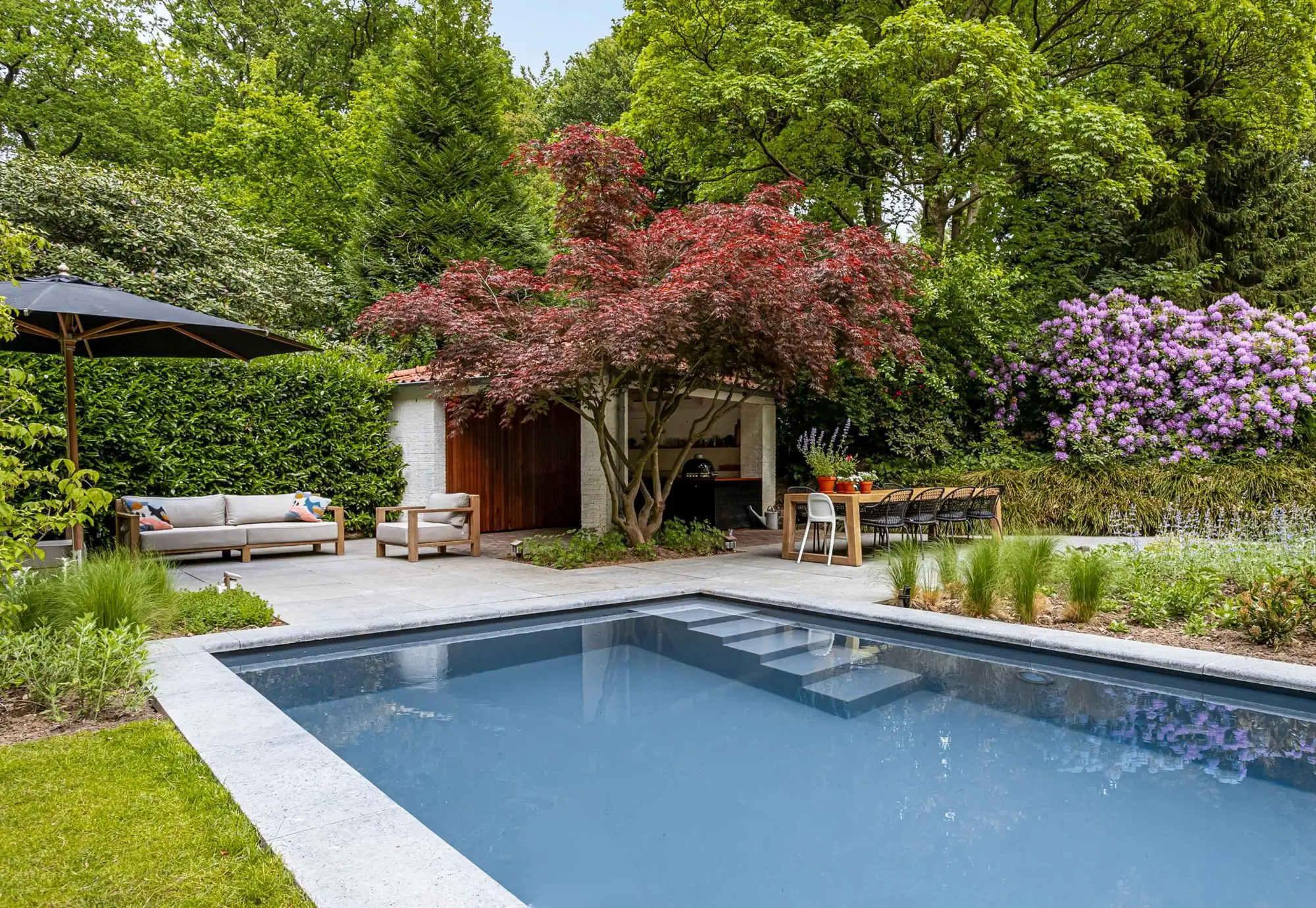 Bostuin met tuinoverkapping en zwembad. Groot terras met buitenkeuken. Tuinontwerp en tuinaanleg door Uw Tuin hoveniers uit Malden. Oase in het groen met groot groen grasveld.