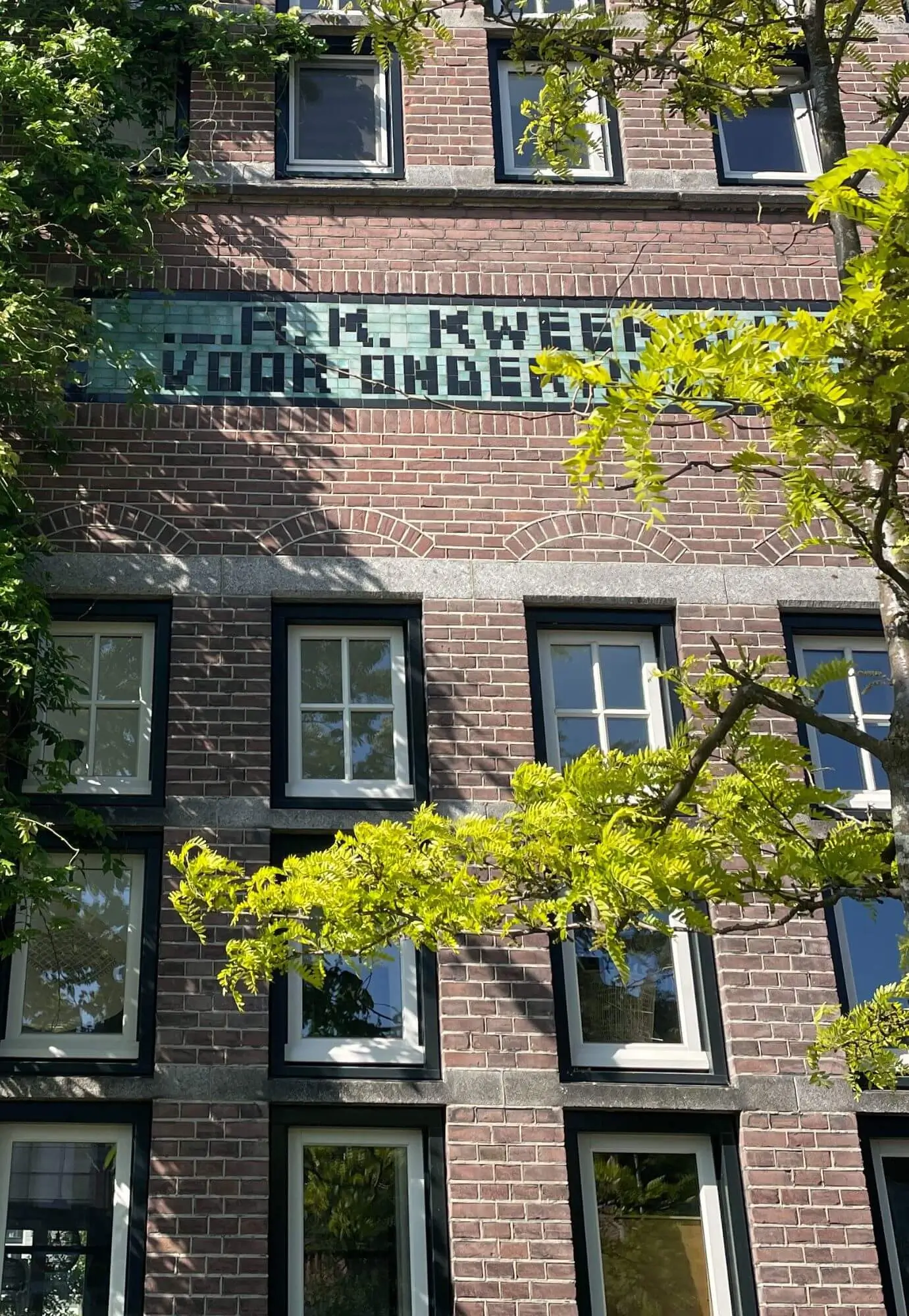 Deatils van het Cum Laude gebouw gecombineerd met groen. Historische kenmerken met klimplanten en zichtbaar tussen het groen.