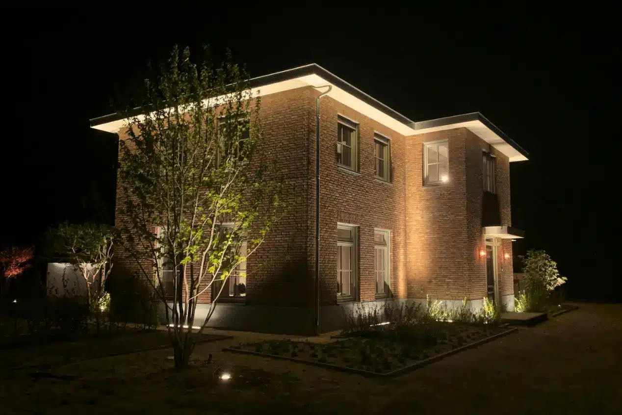 Verlichting op klassieke woning met groen karakter in Malden. Tuinontwerp, tuinaanleg en tuinonderhoud door Uw Tuin hoveniers uit Malden. Zo is uw tuin ook in de avond prachtig verlicht, sfeervol en worden solitaire bomen en heesters prachtig uitgelicht en details in de tuin ook zichtbaar.