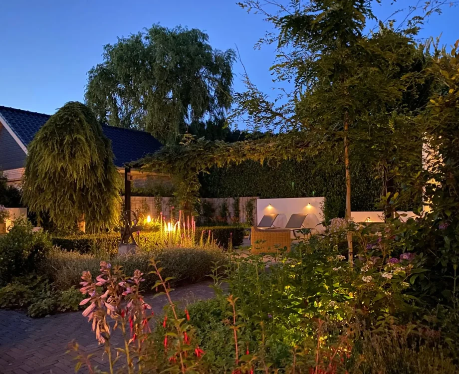 Achtertuin van moderne tuin met jacuzzi in Mook. In de avond sfeervol verlicht door het verlichtingsplan van Uw Tuin hoveniers uit Malden. Tuinontwerp en Tuinaanleg door Uw Tuin hoveniers. Veel groen