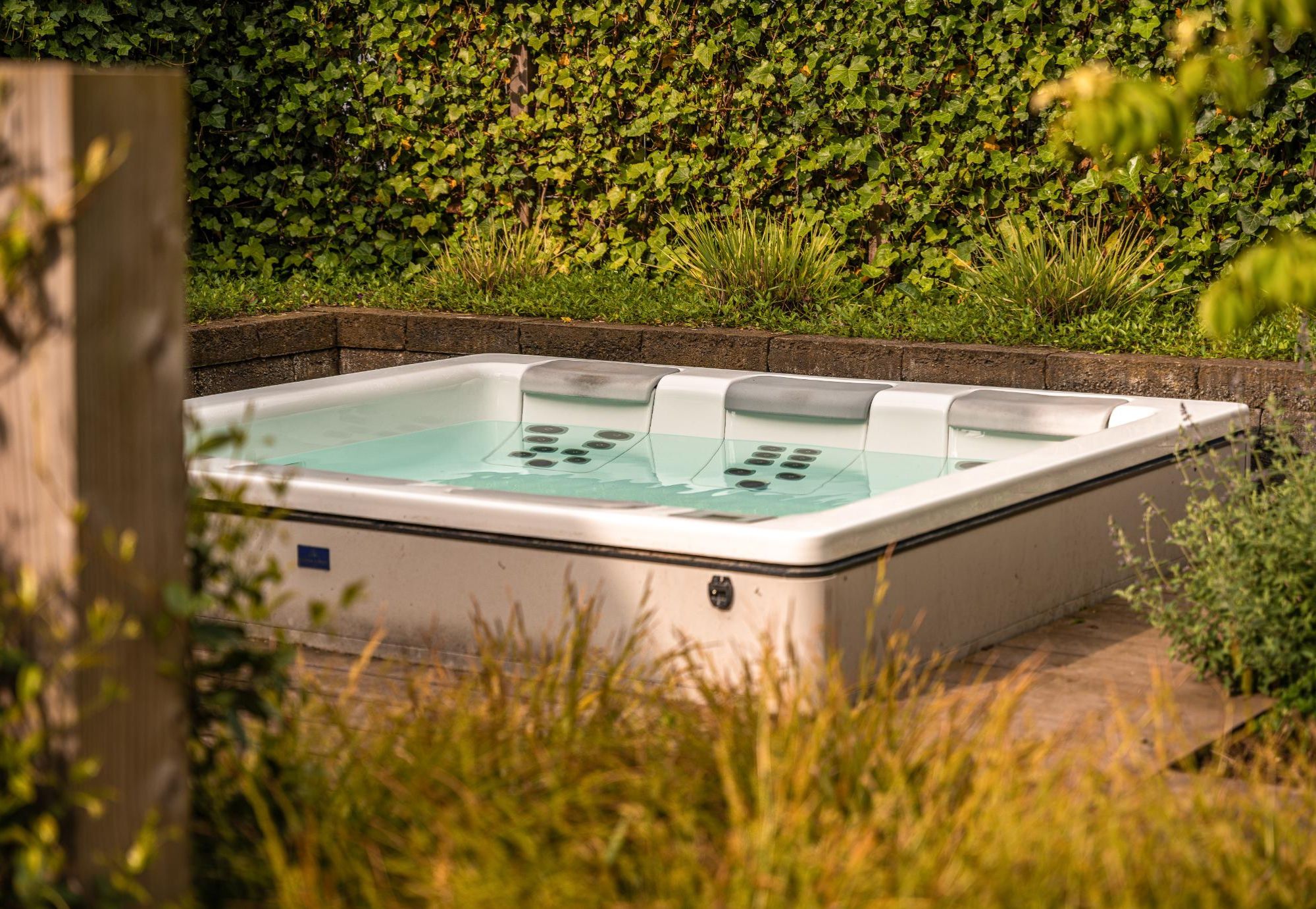 Welness Tuinelementen. Jacuzzi in het groen. Afscherming door palenwand. Tuinaanleg door Uw Tuin hoveniers uit Nijmegen.