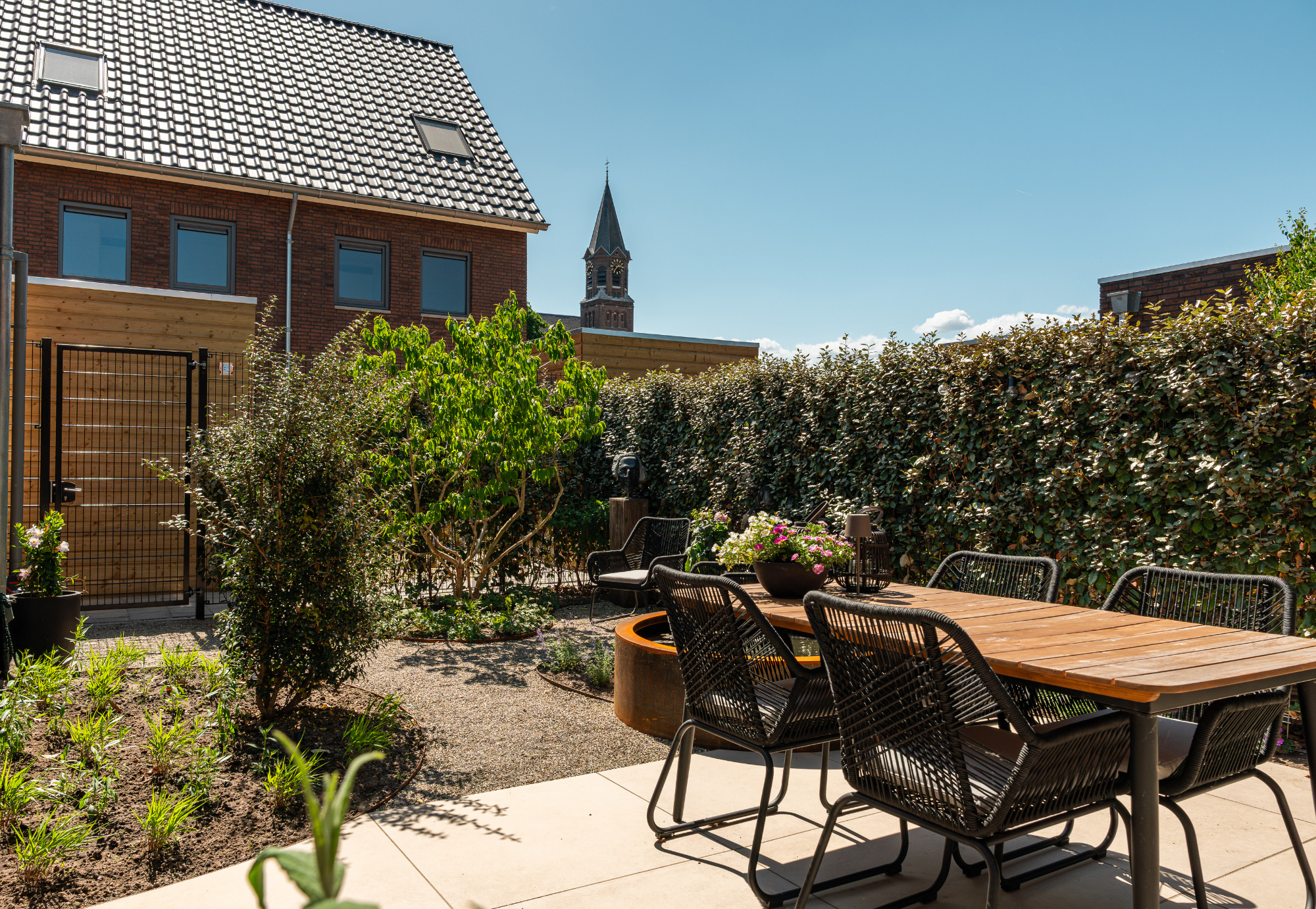 Nieuwbouw stadstuin in Overasselt. Wintergroene erfafscheiding. Keramisch terras, organische vormen met cortenstalen kantopsluiting.